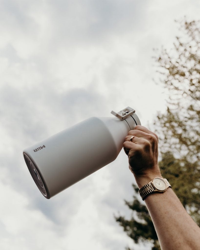 person holding gray and black thermal growler